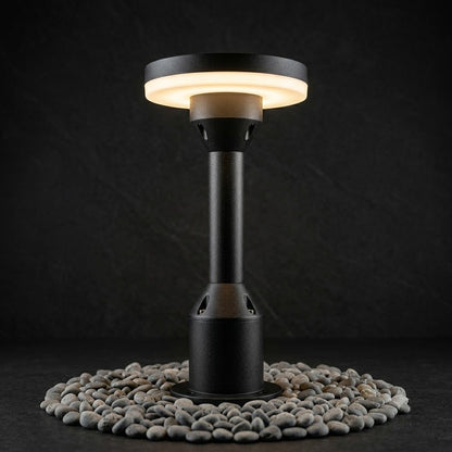 Black outdoor patio heater on a bed of small stones with a dark background