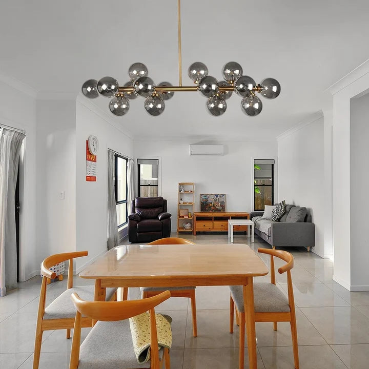 A modern multi-light Crystal Globe Dining Chandelier with reflective silver globe bulbs hangs over a wooden dining table and chairs in a bright, contemporary open-plan living space.